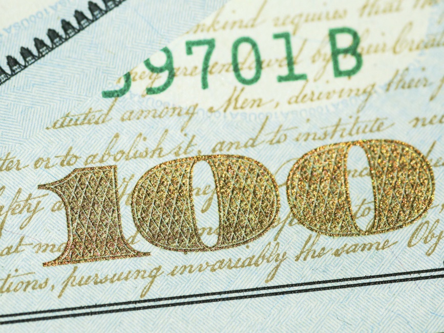 Macro photograph of the engraved numeral on a hundred-dollar bill.